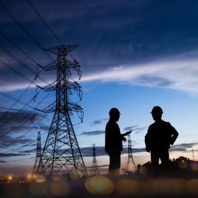 two engineers standing near electrical towers and power lines