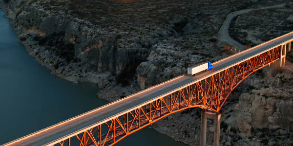 blue truck hauling waste on a bridge